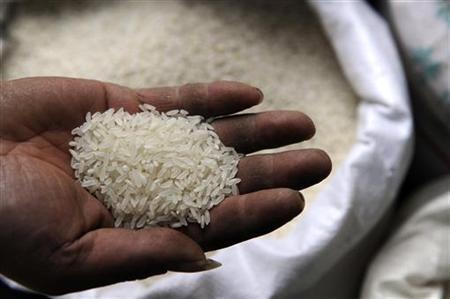 A worker displays a handful of rice at a market in Hefei